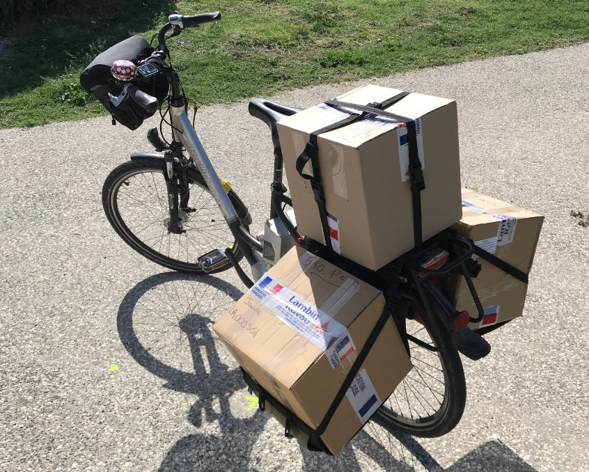 Vélo transportant 2 gros cartons dans ses sacoches Bakkies et un autre sur le porte-bagage